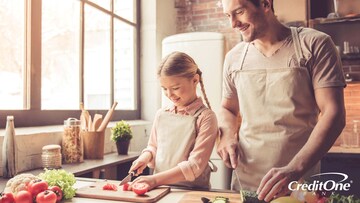 Father and daughter prepping for a meal at home by slicing tomatoes